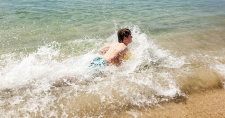happy boy enjoys surfing in the waves at the beachの写真素材