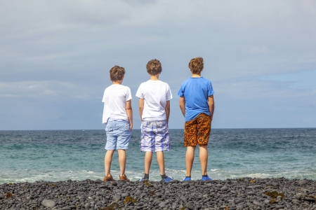 boys have fun at the black volcanic beachの写真素材