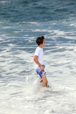 boy has fun in the spume at the black volcanic beachの写真素材