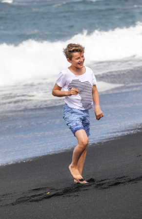 boy has fun in the spume at the black volcanic beachの写真素材