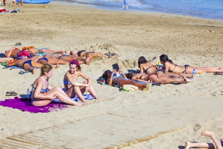 PLAYA BLANCA, SPAIN - APRIL 4: people enjoy the artifical beach Playa Dorada on April 4,2012 in Playa Blanca, Spain. The beach was restored in 2010 with white sand and is the top beach in Lanzarote.の写真素材