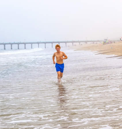 attractive young boy jogging at the beachの写真素材