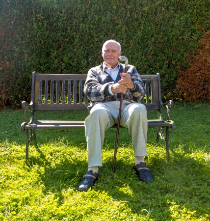 old man enjoys sitting on a bench in his gardenの写真素材