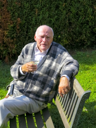 old man enjoys sitting on a bench in his gardenの写真素材