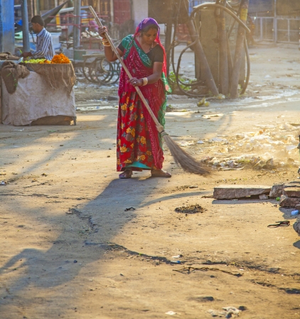 JODHPUR, INDIA - 23 NOVEMBER: woman of fourt class in brightly colored clothing cleans the street on November 23,2012 in Jodhpur, India. They earn 300 IRP for two hours paid by the government.のeditorial素材