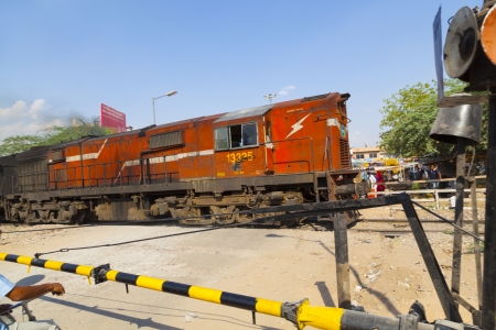 JAIPUR, INDIA - OCTOBER 23: Indian Railway train passes a railroad crossing on October 23, 2012 in Jaipur, India. Indian Railways is one of the world's largest railway networks comprising 115,000 km of track over a route of 65,000 km and 7,500 stations.のeditorial素材