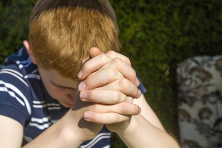 young red haired boy folded his hands in prayerの写真素材