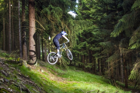 KRONBERG, GERMANY - JULY 7: downhill biker jumps over a ramp in the forest on July 7,2012 in Kronberg, Germany. Downhill racing in forests is planned to regulate by the forest law in 2012.のeditorial素材