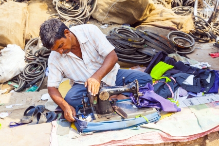 ORISSA, INDIA - NOV 10 - Indian men tailors run their sewing machines in the shade at the weekly market on Nov 10, 2009 in Orissa, India.のeditorial素材