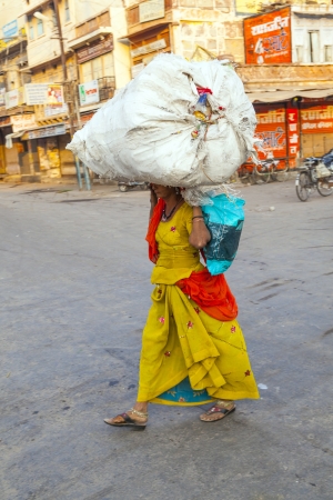 JODHPUR,INDIA - OCT 23: Indian woman carries heavy load on her head in Jodhpur, India. Indian women work more than men but their work is hardly recognized as they do unskilled work.のeditorial素材