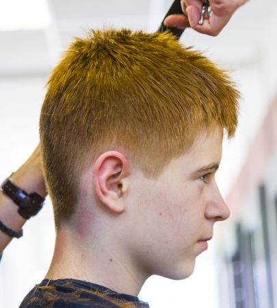 boy at the hairdresser, she is cutting - close-up with selective focus on the noseの写真素材