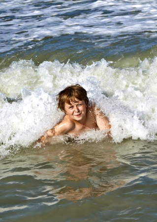 child has fun in the waves of the oceanの写真素材