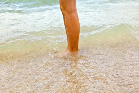 feet of boy running along the beach in the waterの写真素材
