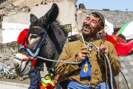 PINGYAO, CHINA - SEP 19: laughing man with old pipe on Sep 19,2011 in Pingyao, China. Donkeys are in the contryside still important for transportation.のeditorial素材