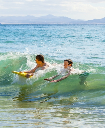boys have fun riding in the wavesの写真素材