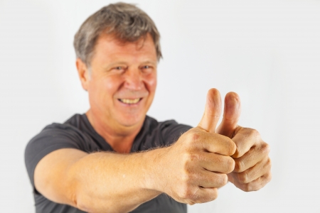 attractive man shows double thumbs up and smiles, focus on thumbの写真素材