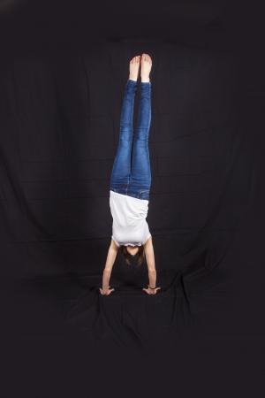 girl performs a handstand in the studio isolated on black