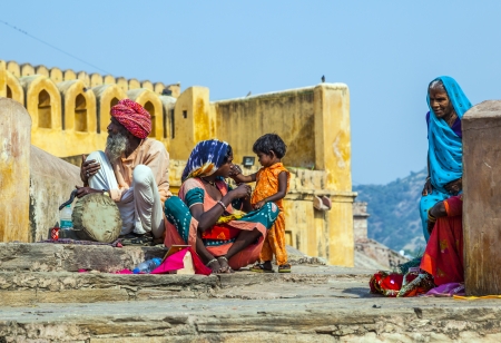 JAIPUR, INDIA - OCTOBER 19  woman begs for money with her child,sitting at the entrance of AMber Fort on October 19, 2012 in Jaipur, India  Begging with children is popular at touristic spots  An old snake charmer sits beside her のeditorial素材