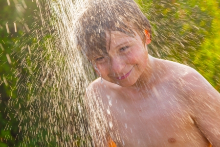boy has a shower at the beach after swimming in the oceanの写真素材