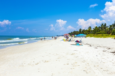 NAPLES, USA - JULY 27: people enjoy the beautiful public white beach at Naples Pier on July 27, 2013 in Naples, USA. The beach is lively and is lined with some of Naples' most luxurious homes, many visible from atop the pierのeditorial素材