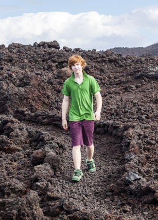 boy walking on volcanic stones in natural parc in lanzaroteの写真素材