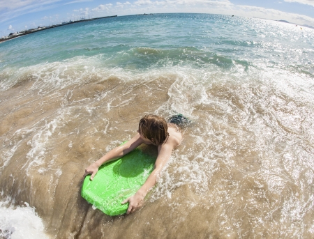 boy has fun with the surfboard at the beachの写真素材