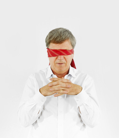 businessman with necktie covering his eyes symbolizing blindness at workの写真素材