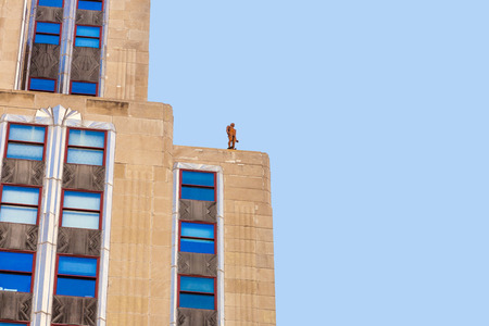 NEW YORK, USA â JULY 11, 2010: Facade of Empire State Building in the afternoon with iron statue of Man on the roof in New York, USA. British Artist Antony Gormley installed the iron man.のeditorial素材