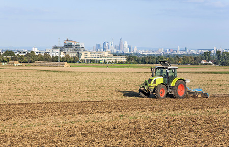 SULZBACH, GERMANY - SEP 12, 2009: tractor is running on the acre plowing the earth in golden light in Sulzbach, Germany. The Rhein-Main area is caracterized by mixture between farming, industry and office Jobs.のeditorial素材
