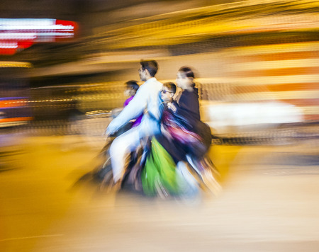 DELHI, INDIA - NOVEMBER 10, 2011: Street traffic in Delhi. Senior man transports on motor bike the whole family in Delhi, India. Old buildings and cars in background. Panning, motion blur.のeditorial素材
