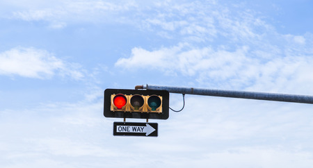 red traffic light with one way sign under blue skyの写真素材