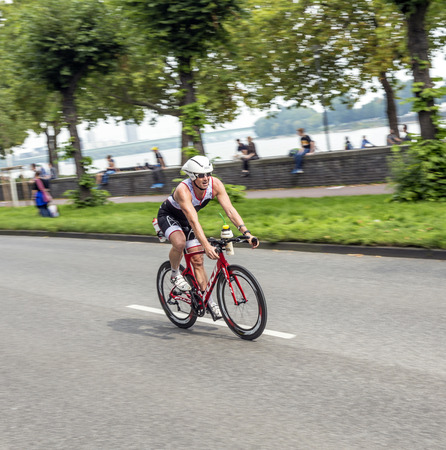 Photo pour COLOGNE, GERMANY- SEP 7, 2014: An athlete cycles in the Cologne Triathlon in Cologne, Germany. The event takes place first in 1984 and is performed ince then yearly in the City area of Cologne. - image libre de droit