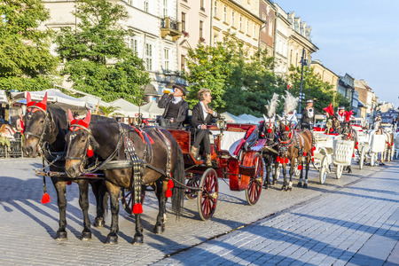 KRAKOW, POLAND - OCT 7, 2014: Horse carriages in front of Mariacki church on main square of Krakow city. Taking a horse ride in a carriage is very popular among tourists visiting Krakowのeditorial素材