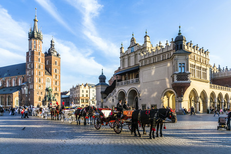 KRAKOW, POLAND - OCT 7, 2014: Horse carriages in front of Mariacki church on main square of Krakow city. Taking a horse ride in a carriage is very popular among tourists visiting Krakowのeditorial素材