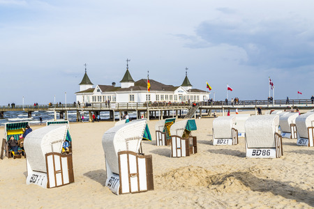 AHLBECK, GERMANY - APRIL 20, 2014: people enjoy pier and beach of Ahlbeck, Germany. The baltic Sea in Usedom Island is famous for its unique  roofed wicker beach chairs.のeditorial素材