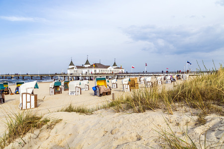 AHLBECK, GERMANY - APRIL 20, 2014: people enjoy pier and beach of Ahlbeck, Germany. The baltic Sea in Usedom Island is famous for its unique  roofed wicker beach chairs.のeditorial素材