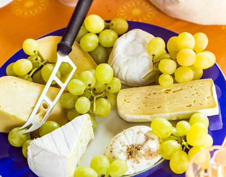 cheese plate with grapes and knife at a blue plateの写真素材