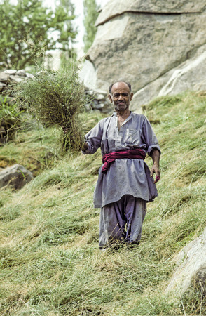 KARIMANBAD, PAKISTAN - SEP 30, 1985: farmer proudly shows fresh hay near Karimabad, Pakistan. Local people are mostly farmers and work in the Hunza region mostly manually.のeditorial素材