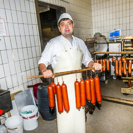 HOESBACH, GERMANY - OCT 15, 2009: butcher prepares fresh sausage in Hoesbach, Germany. The average person in Germany will consume up to 61 kg  of meat in a year.のeditorial素材