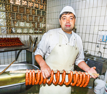 HOESBACH, GERMANY - OCT 15, 2009: butcher prepares fresh sausage in Hoesbach, Germany. The average person in Germany will consume up to 61 kg  of meat in a year.のeditorial素材
