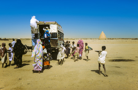 SHENDI, SUDAN - JAN 22, 1986: people try to get on an overland bus in Shendi, Sudan. Boy sells roasted peanuts. Public transportation in Sudan in the desert is more luck than timetable driven.のeditorial素材