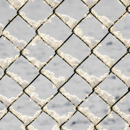 snow covered white metal fence in winterの写真素材