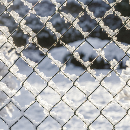 snow covered white metal fence in winterの写真素材