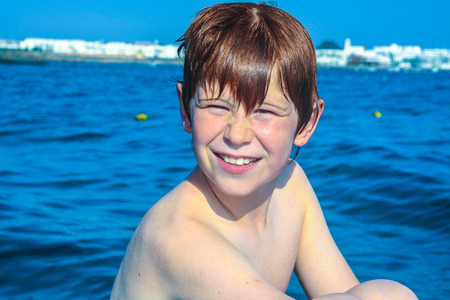cute boy on a boat with wet skin is happy and enjoys the tripの写真素材