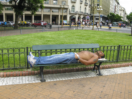 BUENOS AIRES, ARGENTINA, JAN 26, 2015: man sleeps on a bench in Buenos Aires, Argentina. The unemployment rate in Buenos Aires rose to 8,1 percent in 2015.のeditorial素材