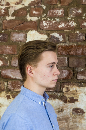 portrait of cute teenage boy in front of grungy brick wallの写真素材
