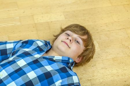 young boy lying at the floorの写真素材