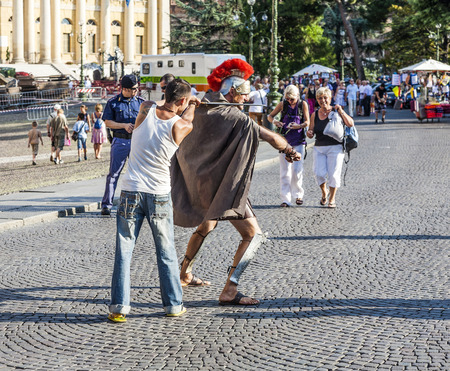 VERONA, ITALY - AUG 5, 2009: people at the place in fromt of the roman amphitheater of Verona, Italy. An actor offers his services as souvenir picture model to tourists.のeditorial素材