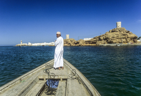 SUR, OMAN - JULY 6, 1996: arabic ferry man transports passenger in an old traditional boat to the island side of Sur, Oman.のeditorial素材