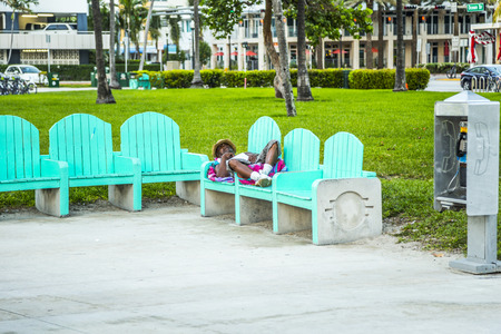MIAMI, USA - AUG 7, 2013: homeless people sleep on a bench in South Beach, Miami, USA. In DEC 2013 only 4,832 people had been living on the street  throughout Miami-Dade County.のeditorial素材